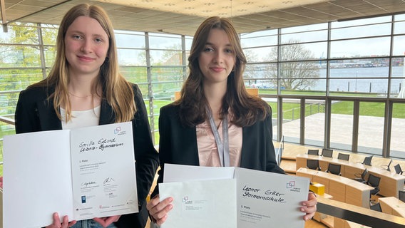 Zwei Schülerinnen mit Urkunde stehen auf der Tribüne im Plenarsaal des Kieler Landeshauses. © NDR Foto: Friederike Hoppe