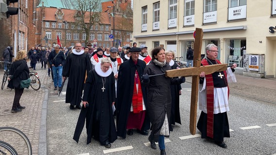 Mehrere Menschen laufen mit einem Kreuz durch die Lübecker Altstadt © NDR Foto: Linda Ebener