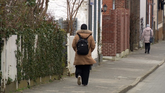 Eine Frau mit Kopftuch geht eine Straßen entlang. © NDR 