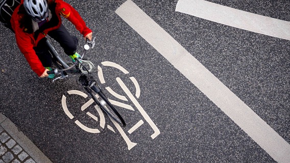 Auf einer Straße in Lübeck markiert ein Fahrradsymbol den Radweg. © IMAGO / Agentur 54 Grad 