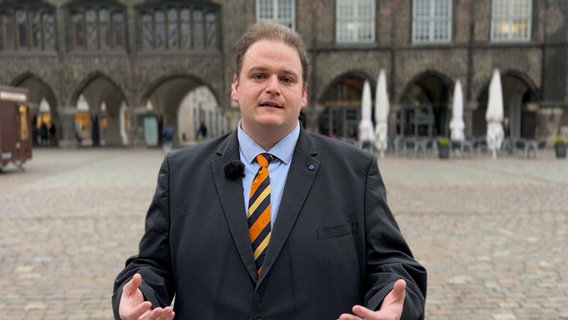 Gregor Voht (Freie Wähler) lächelt auf dem Lübecker Marktplatz in die Kamera. © NDR 
