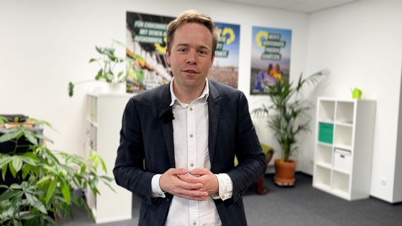 Rasmus Andresen (B90/Die Grünen) lächelt in einem Büroraum in die Kamera. © NDR 