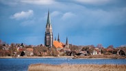 Der St. Petri-Dom zu Schleswig vor blauem Himmel, umgeben von der Ortschaft und Wasser. © Olaf Pinn Foto: Olaf Pinn