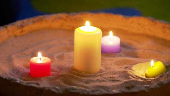 Verschiedene bunte Kerzen sind angezündet. © NDR 