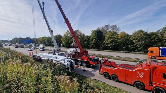 Ein Lkw mit Anhänge liegt nach einem Unfall auf der A1 bei Barsbüttel auf der Seite und wird von einem mobilen Kran geborgen. © Autobahnpolizei Bad Oldesloe 