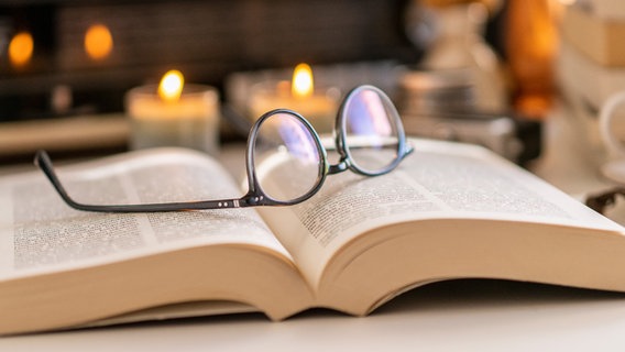 Eine Brille liegt auf einem Geschichtsbuch. © NDR 
