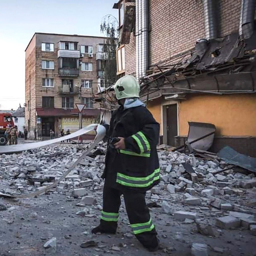 Ein Feuerwehrmann vor einem durch einen russischen Raketenwerfer beschädigtes Gebäude im ukrainischen Dnipro. © Uncredited/Ukrainian Emergency Service/AP/dpa 