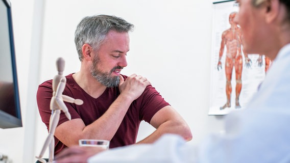 Ein Mann sitzt mit Schulterschmerzen  beim Arzt. © picture alliance / dpa Themendienst Foto: Christin Klose