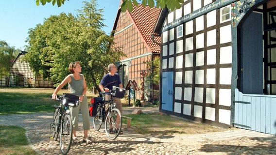 Zwei Radfahrer betrachten ein Haus im Rundlingsdorf Satemin. © picture alliance / dpa Foto: Hans-Jürgen Wege
