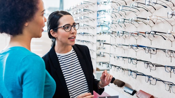 Eine Kundin und eine Optikerin stehen vor einem Regal mit Brillen. © Colourbox Foto: Kzenon