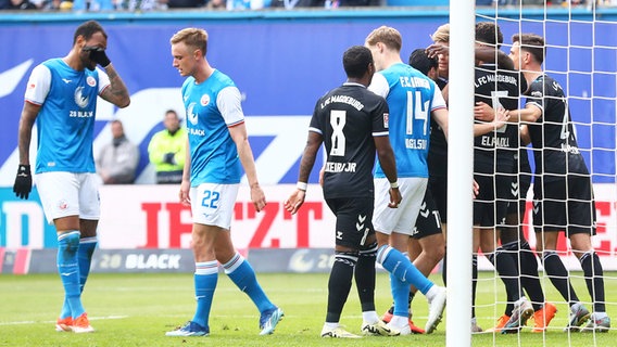 Rostocks Spieler sind enttäuscht, während im Magdeburgs Spieler einen Treffer bejubeln. © IMAGO / Jan Huebner 