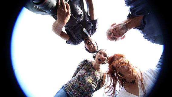 Vier Personen schauen in eine auf dem Boden liegenden Kamera. © photocase.de Foto: time