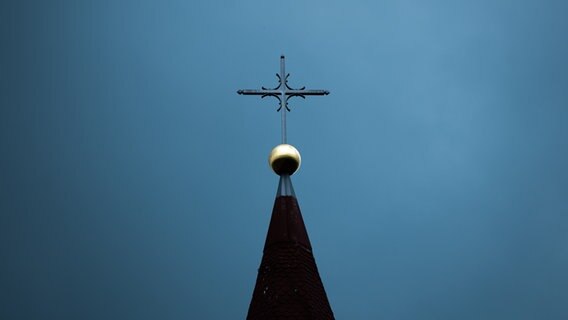 Ein Kreuz auf einer Kirchturmspitze. © dpa Foto: Silas Stein