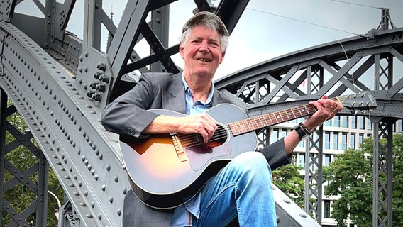 Eddy Winkelmann sitzt mit seiner Gitarre auf der Brücke © Eddy Winkelmann Foto: Eddy Winkelmann