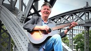 Eddy Winkelmann sitzt mit seiner Gitarre auf der Brücke © Eddy Winkelmann Foto: Eddy Winkelmann