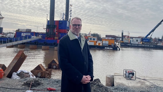 Der Leiter der Generaldirektion Wasserstraßen und Schifffahrt Eric Oehlmann im Portrait. Hinter ihm: ein Hafen. © Wasserstraßen- und Schifffahrtsverwaltung des Bundes (WSV) Foto: Wasserstraßen- und Schifffahrtsverwaltung des Bundes (WSV)