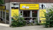 Über einem Hauseingant steht "Bücherstübe Fuhlsbüttel" auf einem gelb leuchtenden, großen Schild. © NDR Foto: Susanne Hasenjäger