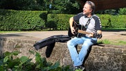 Der Harburger Singer Songwriter Jan Schröder mit seiner Gitarre im Harburger Stadtpark © NDR Foto: Petra Volquardsen