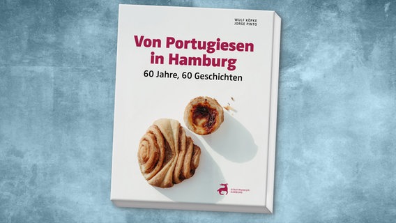 Auf einem weißen Buchcover liegt Gebäck. Es sind ein Franzbrötchen und ein Nata. Von Portugiesen in Hambrug steht in roten Buchstaben darüber. © amh - Archäologisches Museum Hamburg Foto: amh - Archäologisches Museum Hamburg