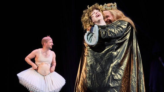 Auf der Bühne umarmt ein König mit goldener Krone und goldenem Umhang eine lachende Frau © Ernst Deutsch Theater  / Oliver Fantitsch Foto: Oliver Fantitsch