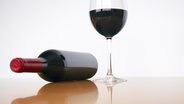 Eine Flasche Wein liegt neben einem gefüllten Rotweinglas. © photocase Foto: markusspiske