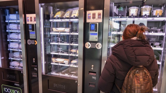 Eine Kundin steht vor einem Automaten mit Lebensmitteln in einem Automatenshop. © picture alliance/dpa/Belga Foto: Nicolas Maeterlinck