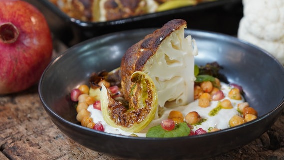 Gerösteter Blumenkohl mit Tahini-Joghurt und Minzpesto auf einem Teller angerichtet. © NDR Foto: Florian Kruck