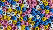 Bunte Buchstaben des Familienspiels "Buchstabensuppe" liegen auf einem Tisch © picture alliance / ZB | Jens Kalaene Foto: Jens Kalaene