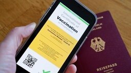 Symbolbild eines möglichen digitalen Impfpasses und eines Deutschen Reisepasses
