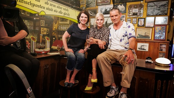 Ina Müller sitzt bei Inas Nacht mit Susanne Daubner und Götz Otto auf dem Tresen. © NDR/Morris Mac Matzen Foto: Morris Mac Matzen