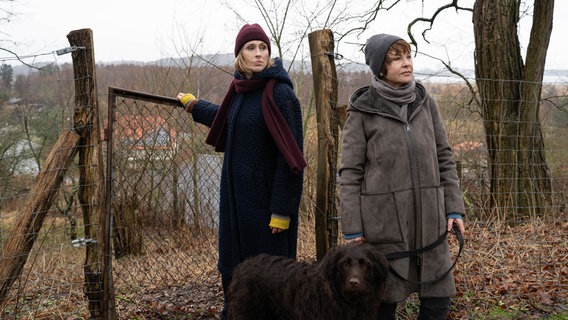 Zwei Frauen stehen mit einem Hund an der Leine an einem Zaun. © NDR/ARD Degeto/Florian Kaposi Foto: Florian Kaposi