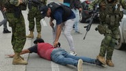 Polizisten in Ecuador verhaften einen Mann, der am Boden liegt © picture alliance Foto: Anadolu Jose Orlando Sanchez Lindao