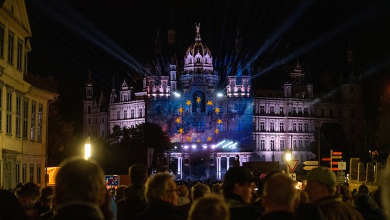 Bei eine Lichtshow, die auf die Fassade des Schweriner Schlosses projiziert wird, können Besucher den Weg von der Friedlichen Revolution 1989 bis heute in Bildern erleben. Im Rahmen der Bundesratspräsidentschaft richtet Schwerin unter dem Motto „Vereint Segel setzen“ die zentralen Feierlichkeiten zum Tag der Deutschen Einheit aus. © picture alliance/dpa | Stefan Sauer Foto: Stefan Sauer