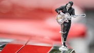 Eine Elvis-Presley-Figur ist auf der Motorhaube eines Oldtimers auf dem Elvis-Festival in Bad Nauheim zu sehen. © Boris Roessler/dpa Foto: Boris Roessler