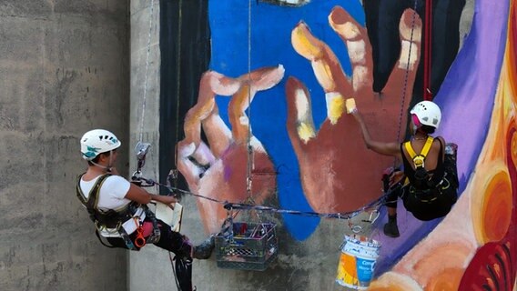 Wandmalerin Maria und Sara Nuru arbeiten in Mexiko in luftiger Höhe an einem neuen Kunstwerk. © NDR/doclights/Tina Muffert 