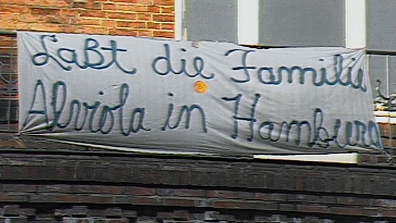 Auf einem Banner steht "Laßt die Familie Alviola in Hamburg". © Screenshot 