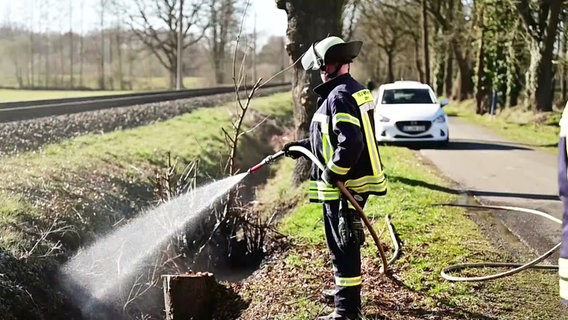 Ein Feuerwehrmann löscht einen Flächenbrand an einem Bahndamm bei Apen. © NonstopNews 