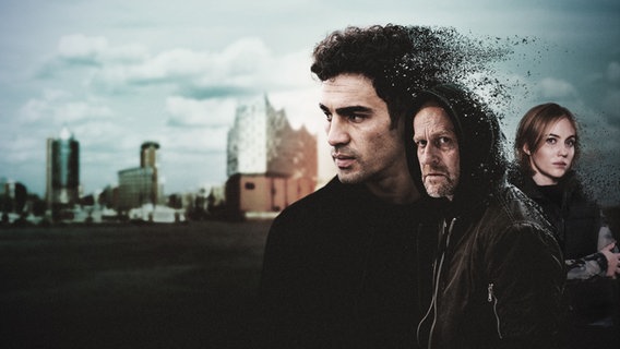 Raza Shaheen (Ivar Wafaei), Gabriel Bach (Jürgen Vogel) und Holly Valentin (Elisa Schlott) im Vordergrund, im Hintergrund die Hamburger Skyline mit Elbphilharmonie. © Boris Laewen/NDR/Viktoria Grunjajew 