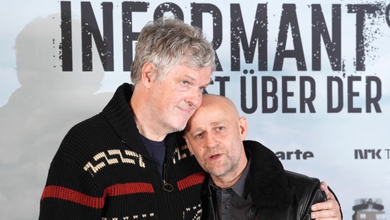 Ein größerer Mann umarmt einen etwas kleineren - Regisseur Matthias Glasner und Jürgen Vogel in der Elbphilharmonie bei einer Filmpremiere ©  Marcus Brandt/dpa +++ dpa-Bildfunk +++ Foto:  Marcus Brandt