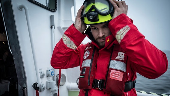 Ein Seenotretter setzt sich einen Helm auf. © Kinescope/Achim Multhaupt 