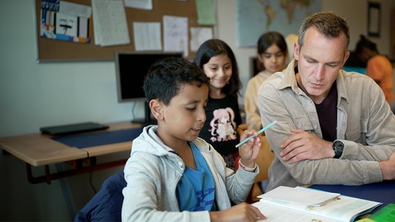 Tobias Lucht hilft einem Schulkind bei den Hausaufgaben. © NDR/Gesa Berg 