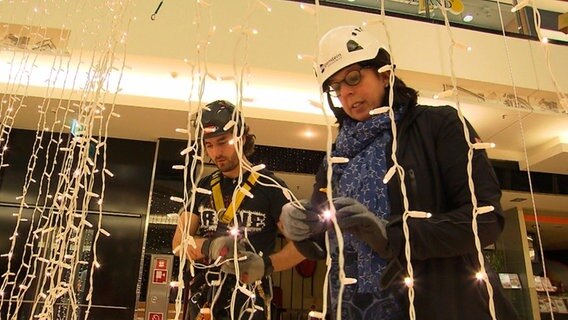 Chefin Annegret und ein Mitarbeiter friemeln unzählige Lichterketten auseinander. © NDR/KameraZwei 
