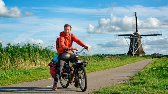 Mit einem "Solex", einem typisch friesischen Moped, erkundet Daniel Aßmann das niederländische Friesland. © WDR/Bavaria Entertainment GmbH/Sarina Zilligers 