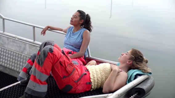 Malika (Salka Weber) und Tümay (Meryem Ebru Öz) entspannen auf dem Deck eines Schiffes. © NDR/Claudia Konerding 