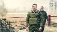 Collage: Vitali und Wladimir Klitschko, gekleidet in eine Militäruniform mit Schutzweste, stehen in einem Boxring. Im Hintergund ist eine ausgebombte Stadt zu sehen. © Sky UK Ltd 