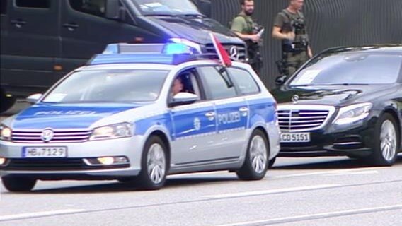 Ein Polizeiwagen führt eine Fahrzeugkolonne an  