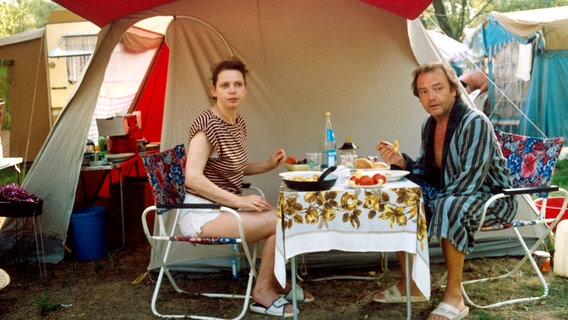 Zeltlager Ungarn 1989: Die Grenze ist offen. Das Ehepaar Wendler (Jürgen Schmidt und Renate Krößner) verfolgt den Aufbruch der Urlauber. Und ehe sie sich versehen, stehen auch sie mitten im Treck gen Westen. © NDR 