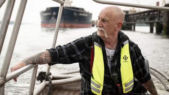 Festmacher Lutz Vellguth sitzt auf einem Boot im Bremer Hafen. © NDR/FILMBLICK Hannover/Michael Ihle 