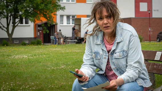 Szenenbild aus der NDR Serie "Reisen mit Muddi": Eine Frau sitzt auf einer Parkbank. © NDR/Boris Laewen Foto: Boris Laewen