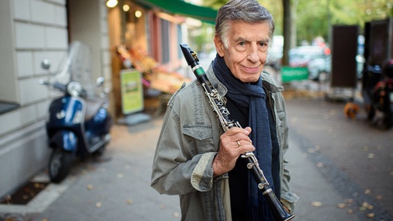 Jazz-Legende Rolf Kühn steht auf einem Gehweg mit seiner Klarinette © Gregor Fischer Foto: Gregor Fischer